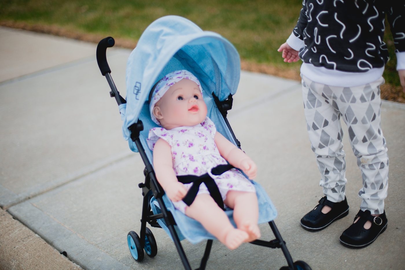 A baby doll dressed up in a Triokid stroller