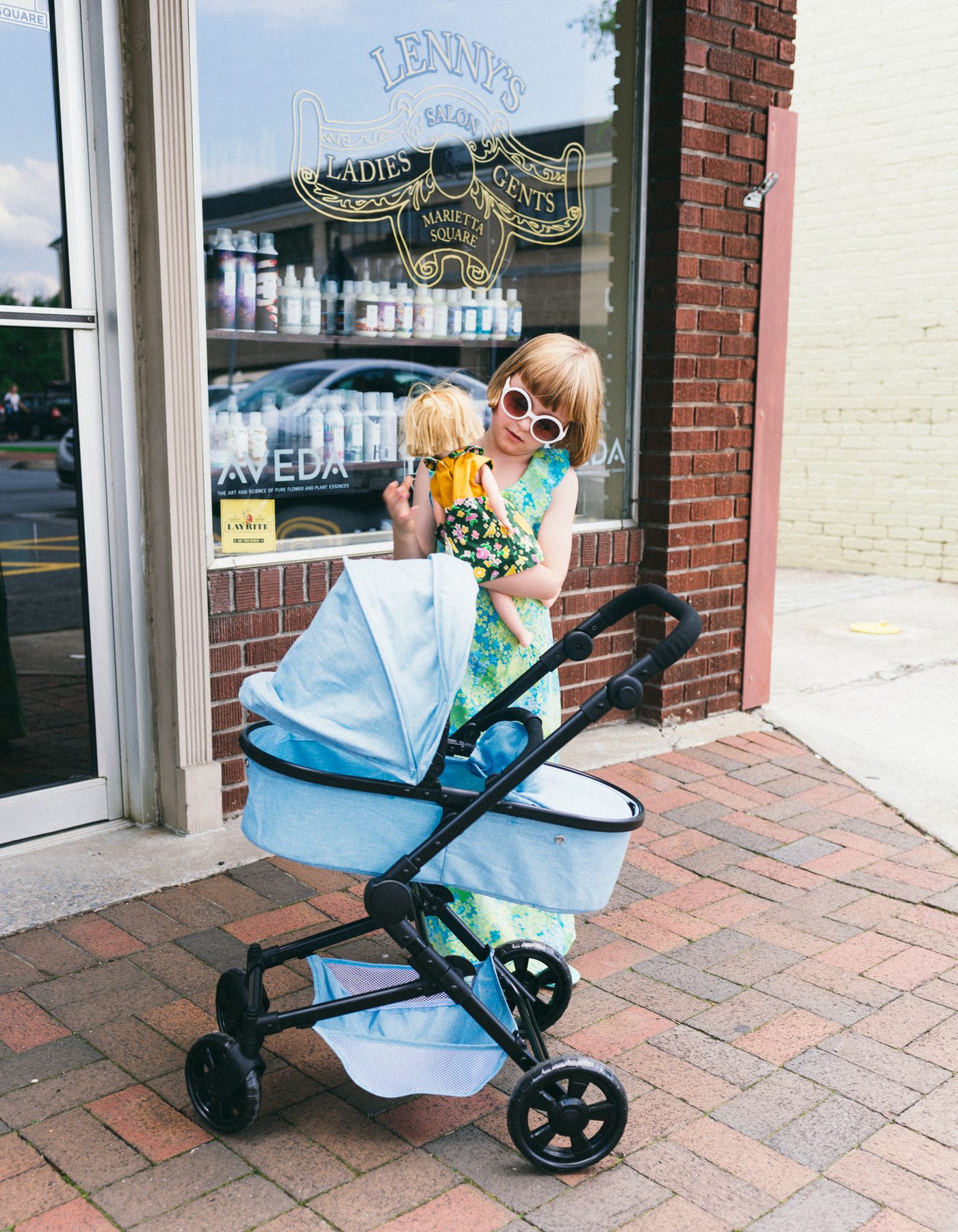 A small carer with her blue pram outside a storefront